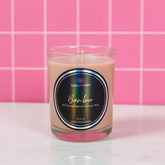 Candle in a glass jar with a label on a pink tiled background
