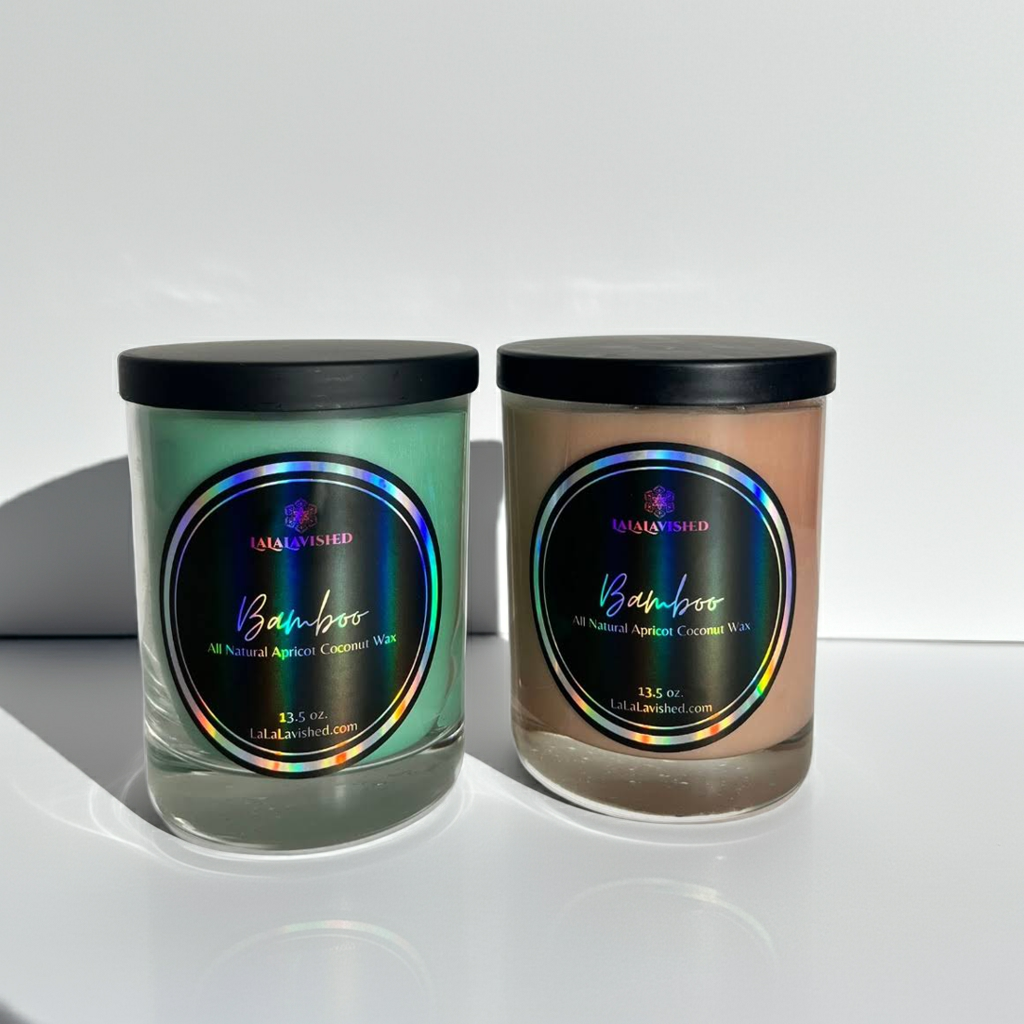 Two candles with black lids on a white surface, featuring &