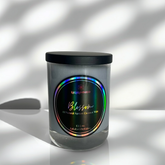 Candle jar with a colorful label on a reflective surface