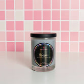 Candle jar with a label on a pink tiled background
