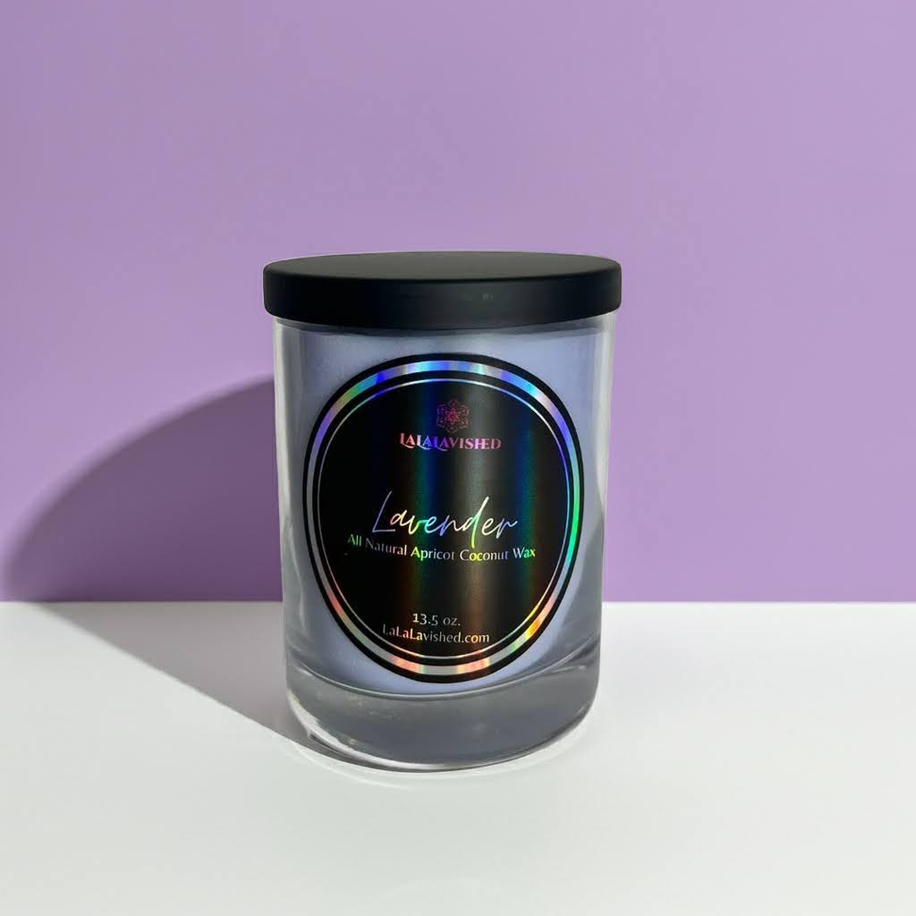 Glass candle with a black lid and colorful label on a white surface with a purple background