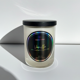 Vanilla-scented candle with a black lid on a white surface