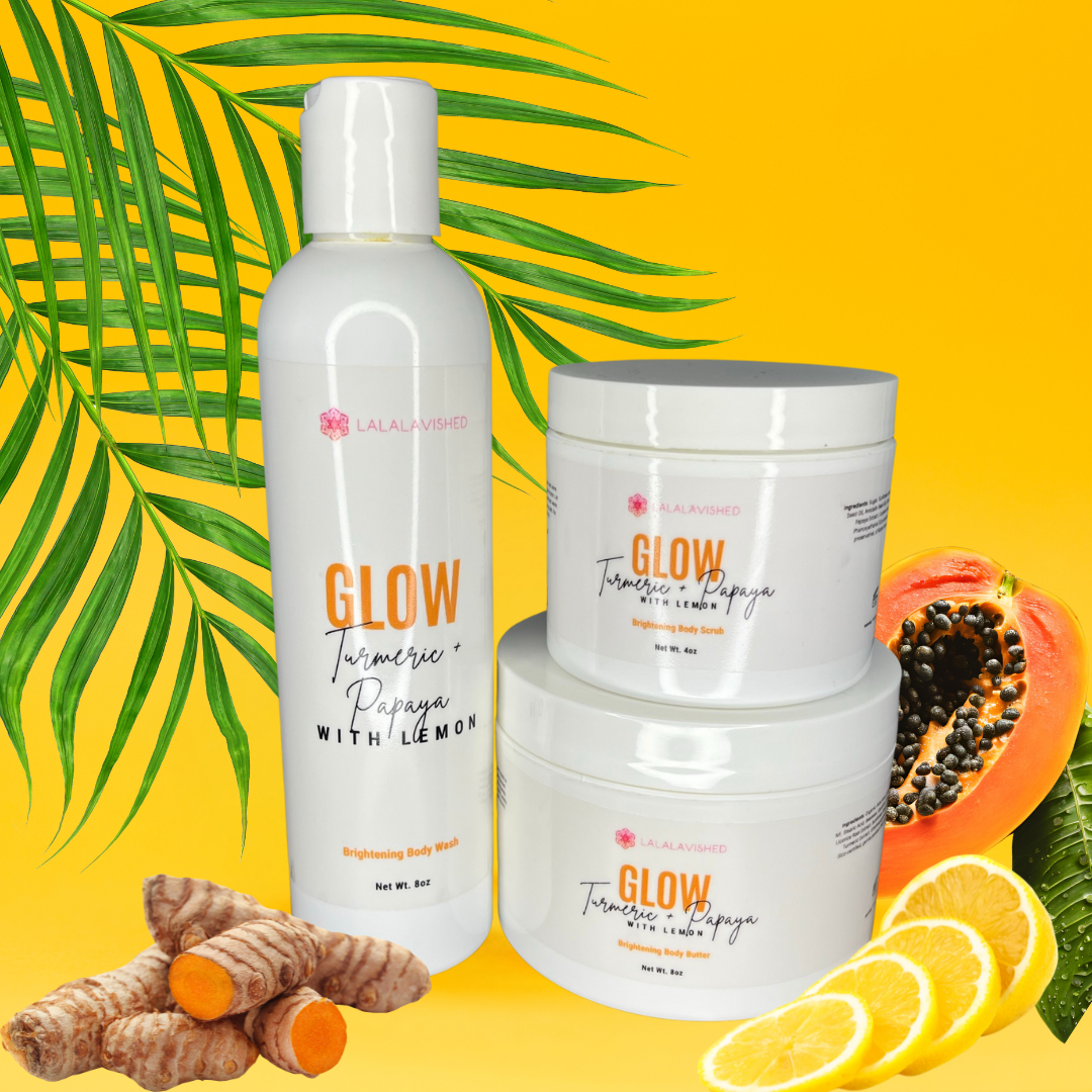 A set of skin care products including a bottle of body wash, a container of body scrub, and a tub of body butter, arranged with decorative elements like fruits and turmeric roots.